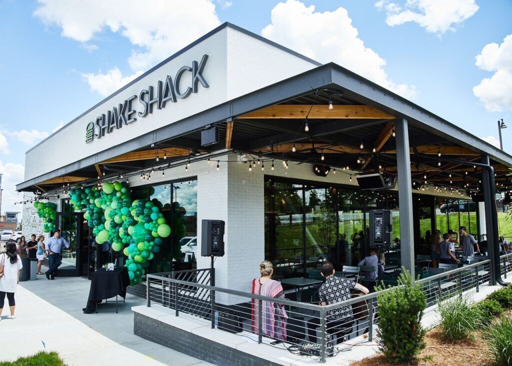 Shake Shack restaurant bruisend van klanten en honderden groene ballonnen aan de voorkant en Gasverwarmers